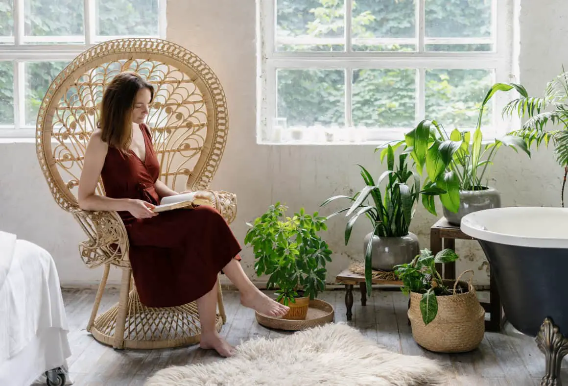 woman-sitting-in-a-wicker-chair-reading-in-a-cozy-bohemian-style-home