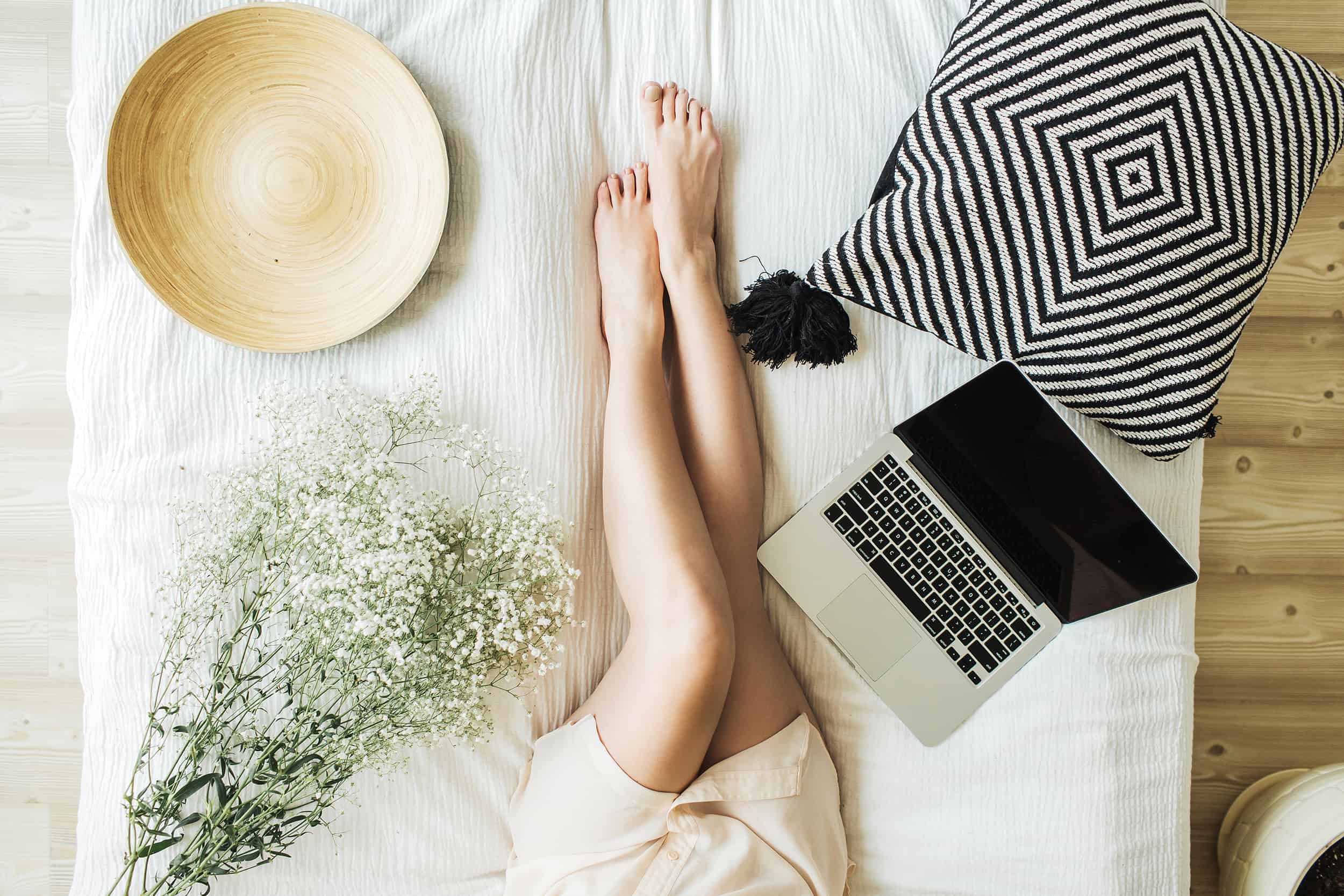 Young-woman-working-on-laptop-in-bed-lifestyle-composition