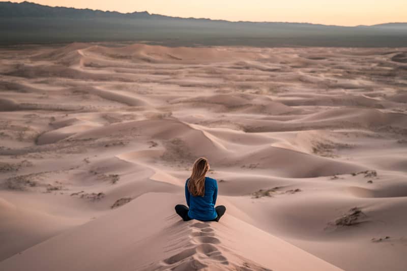 woman-sitting-cross-legged-on-sand-dune