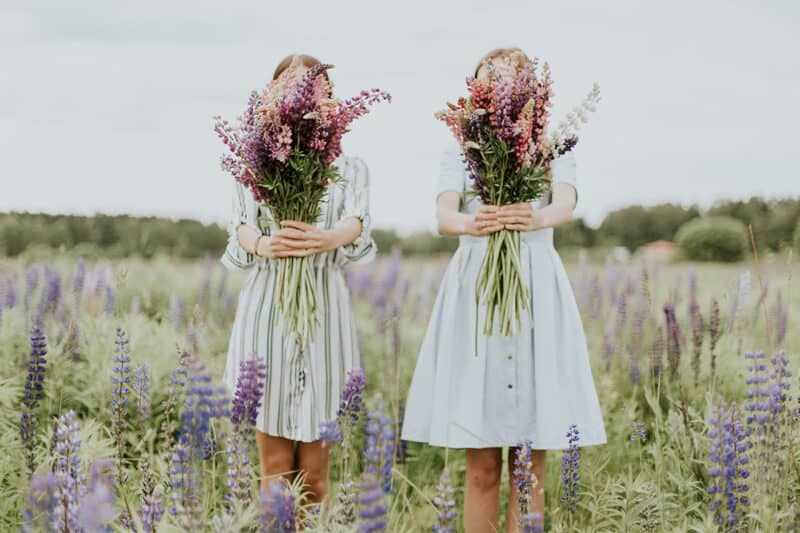 two-young-girls-twin-like-holding-flowers-lavendar-on-a-field-in-nature