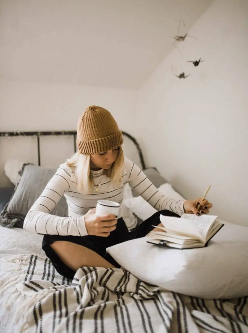 woman-cozy-on-bed-writing-in-manifesting-journal