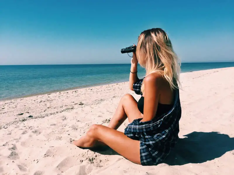 woman-on-beach-using-binoculars-looking-out-into-the distance