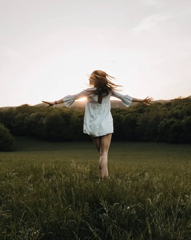 young-woman-in-a-white-dress-spinning-free-spirit-in-a-field-nature