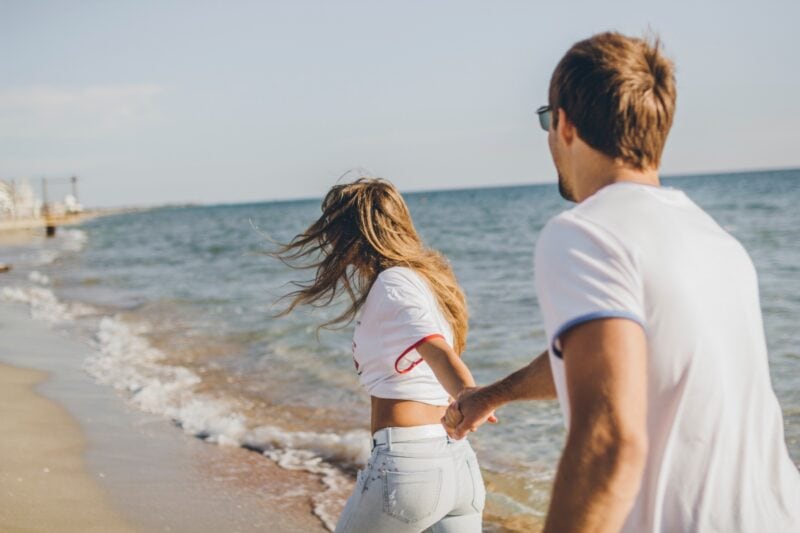 woman-and-man-happy-running-on-the-beach-holding-hands