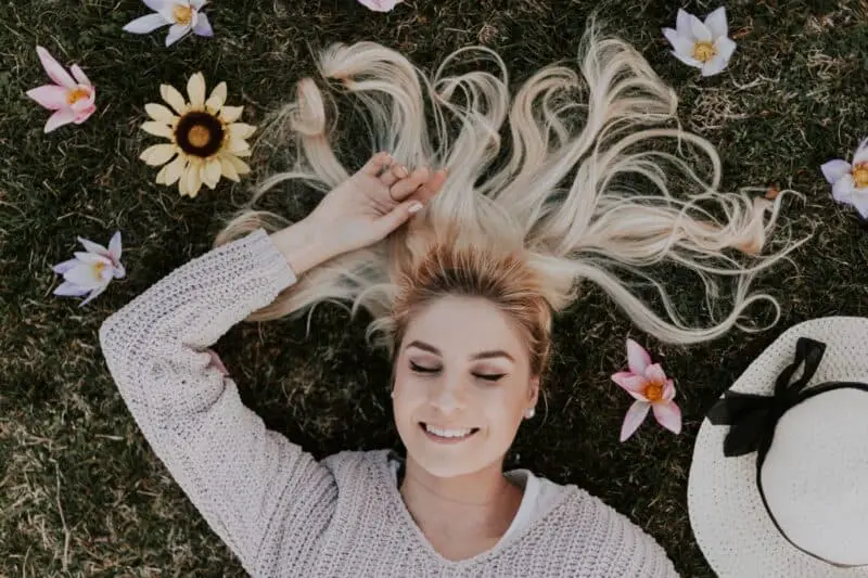 woman-smiling-lying-on-grass-meditating-state-akin-to-sleep-with-flowers