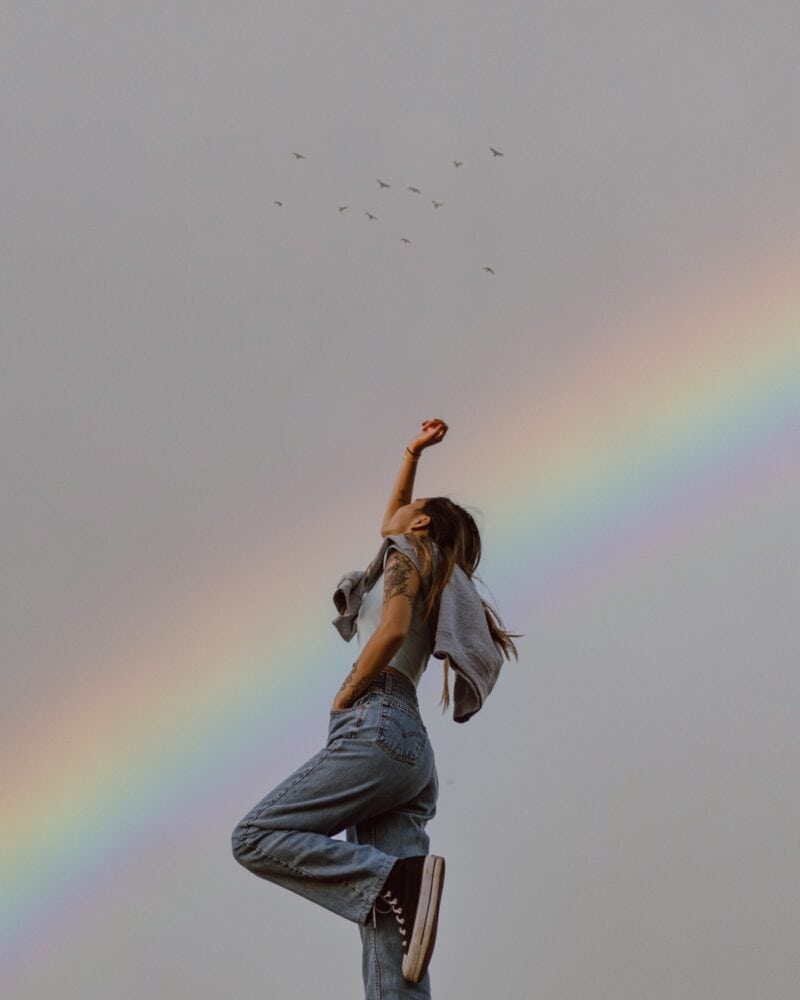woman-standing-raising-arm-rainbow-birds-vibration