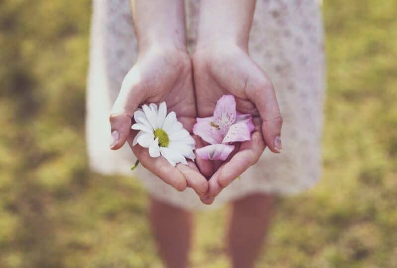 girl-holding-hands-out-with-flowers