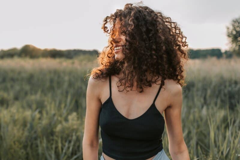 woman-with-curly-hair-in-black-tank-top-in-green-nature