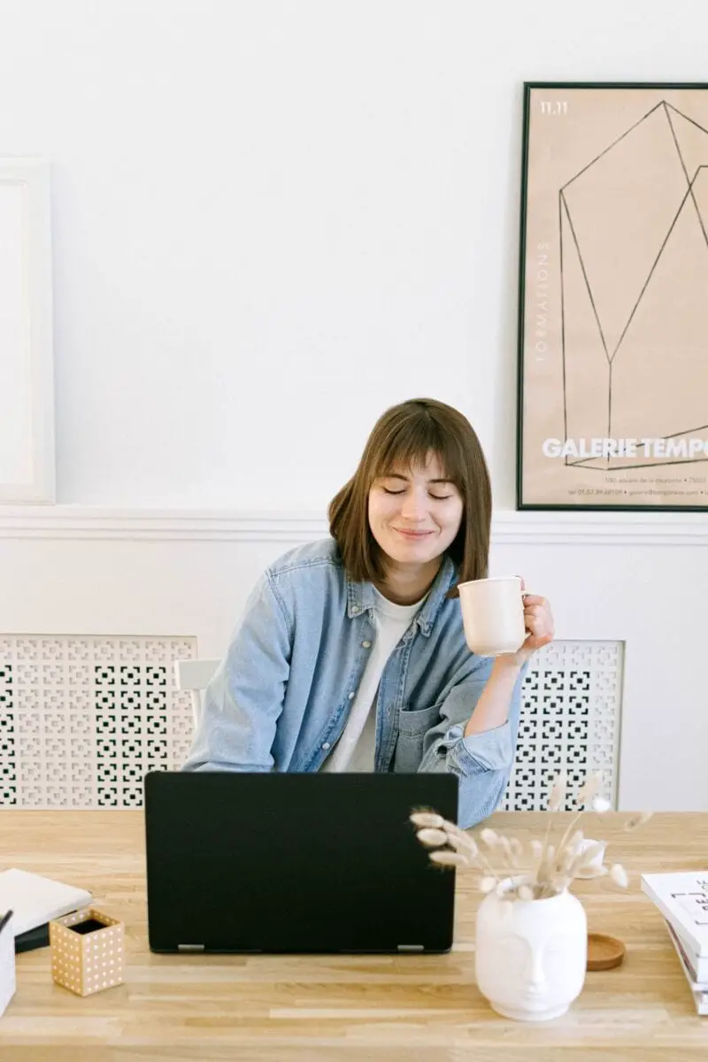 woman-with-short-hair-on-computer-drinking-coffee-working