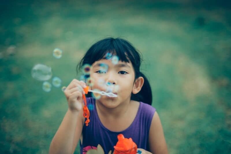 young-girl-with-black-hair-blowing-bubbles
