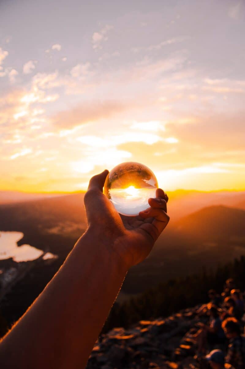 hand-holding-crystal-glass-ball-sunset-sky