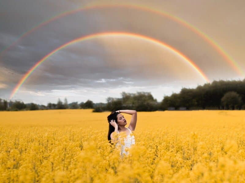 woman-wearing-white-in-yellow-field-with-rainbow