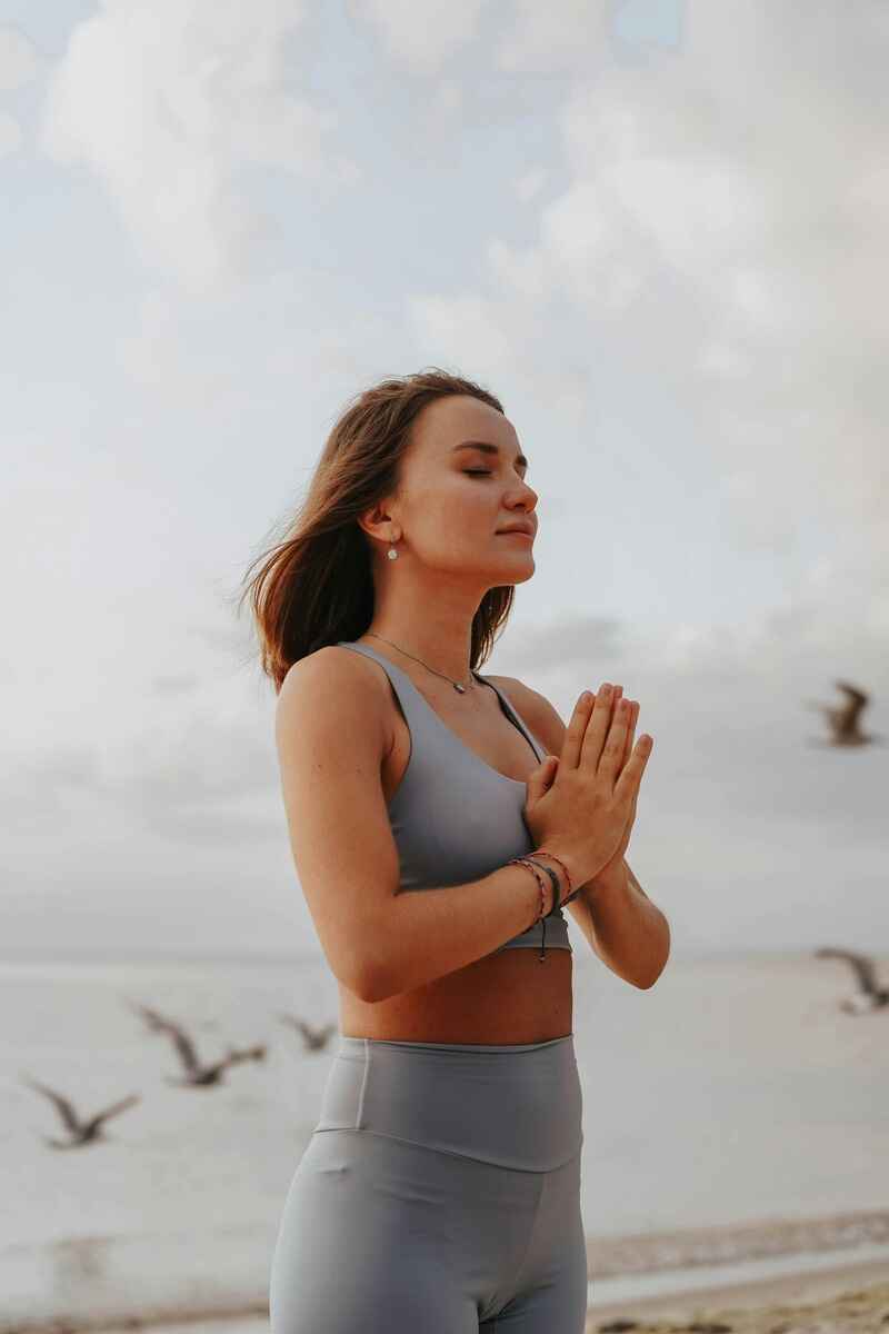 signs-your-manifestation-is-close-woman-praying-in-blue-yoga-clothing-on-the-beach